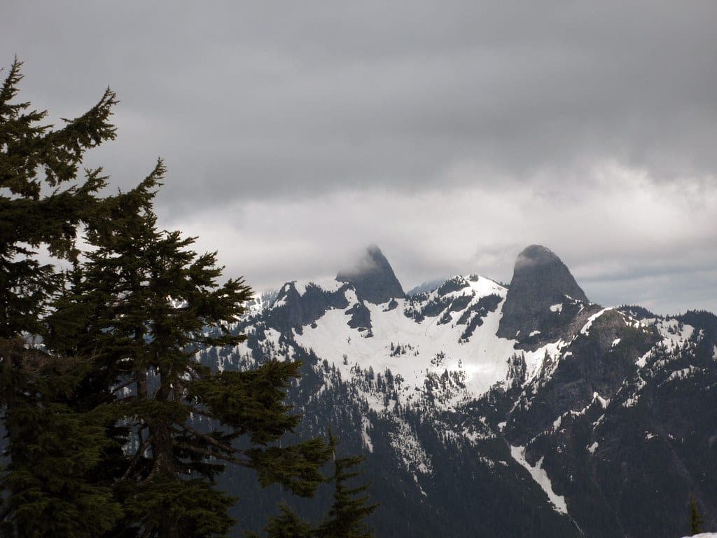 The twin summits of the Lions rise out of cloud and snowfields in a view from Hollyburn Peak.