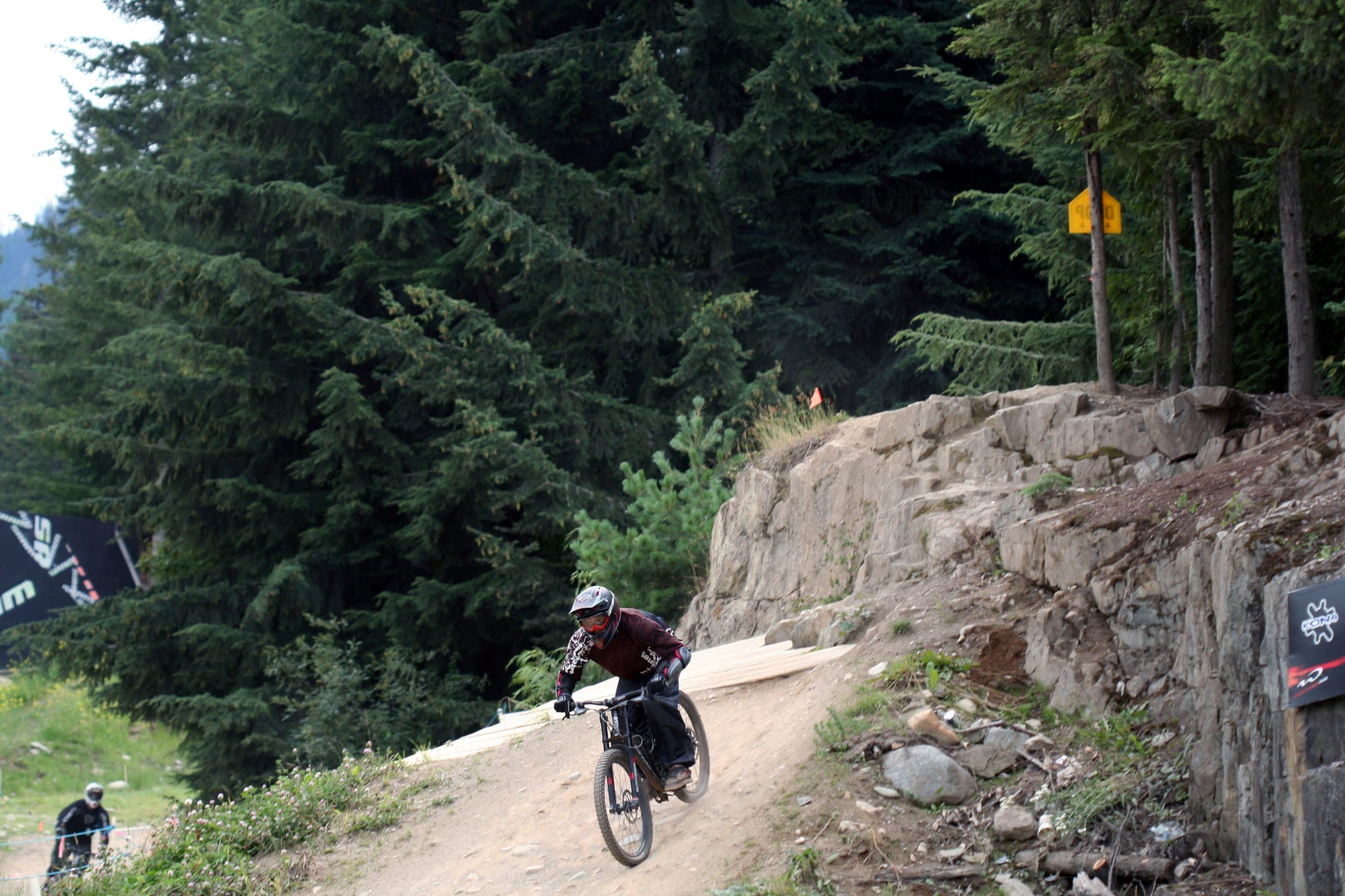 A mountain biker lands a rock drop on a dirt trail at the base of the Whistler Mountain Bike Park.
