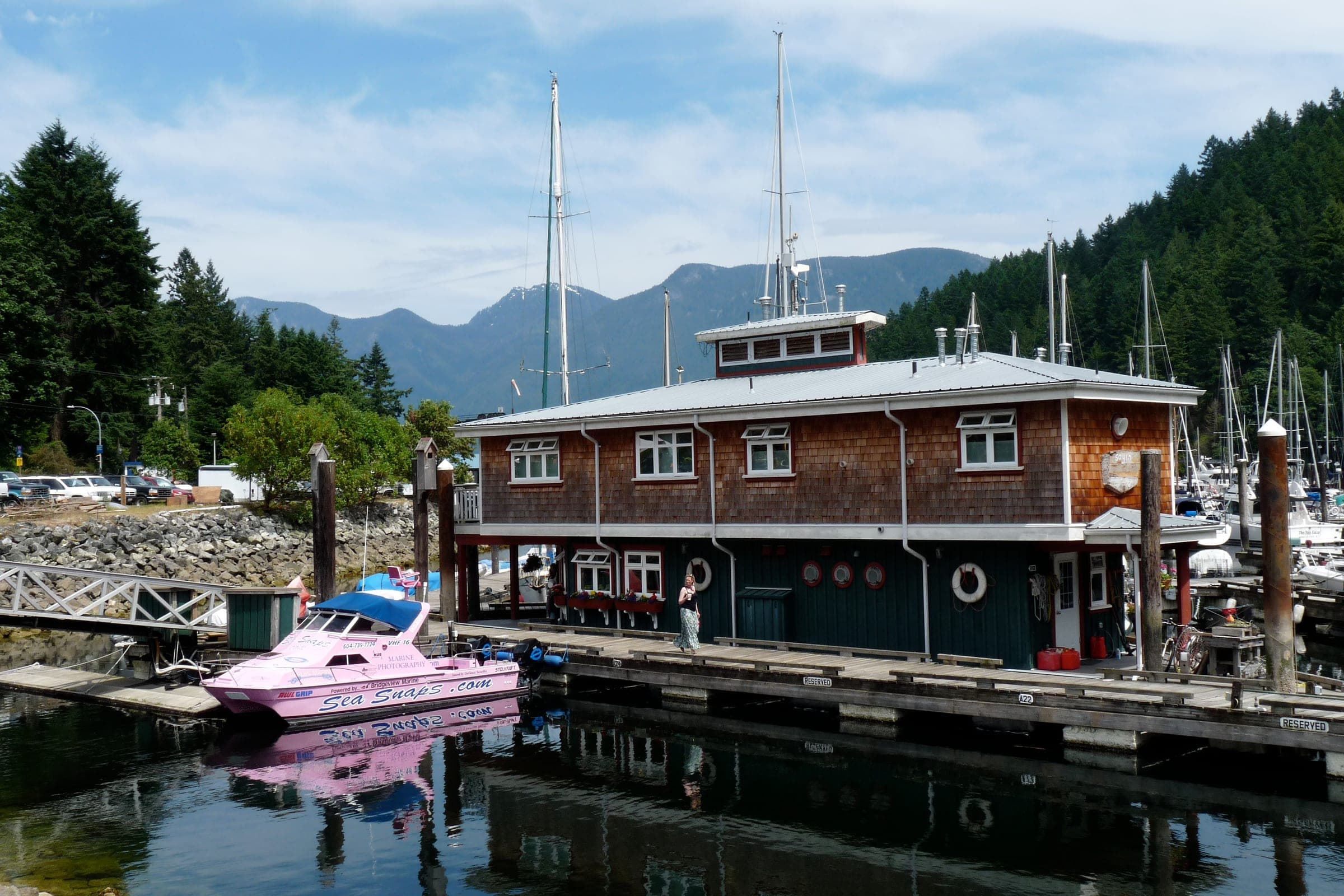 Boats tie up at the Snug Cove marina on Bowen Island below forested hills.