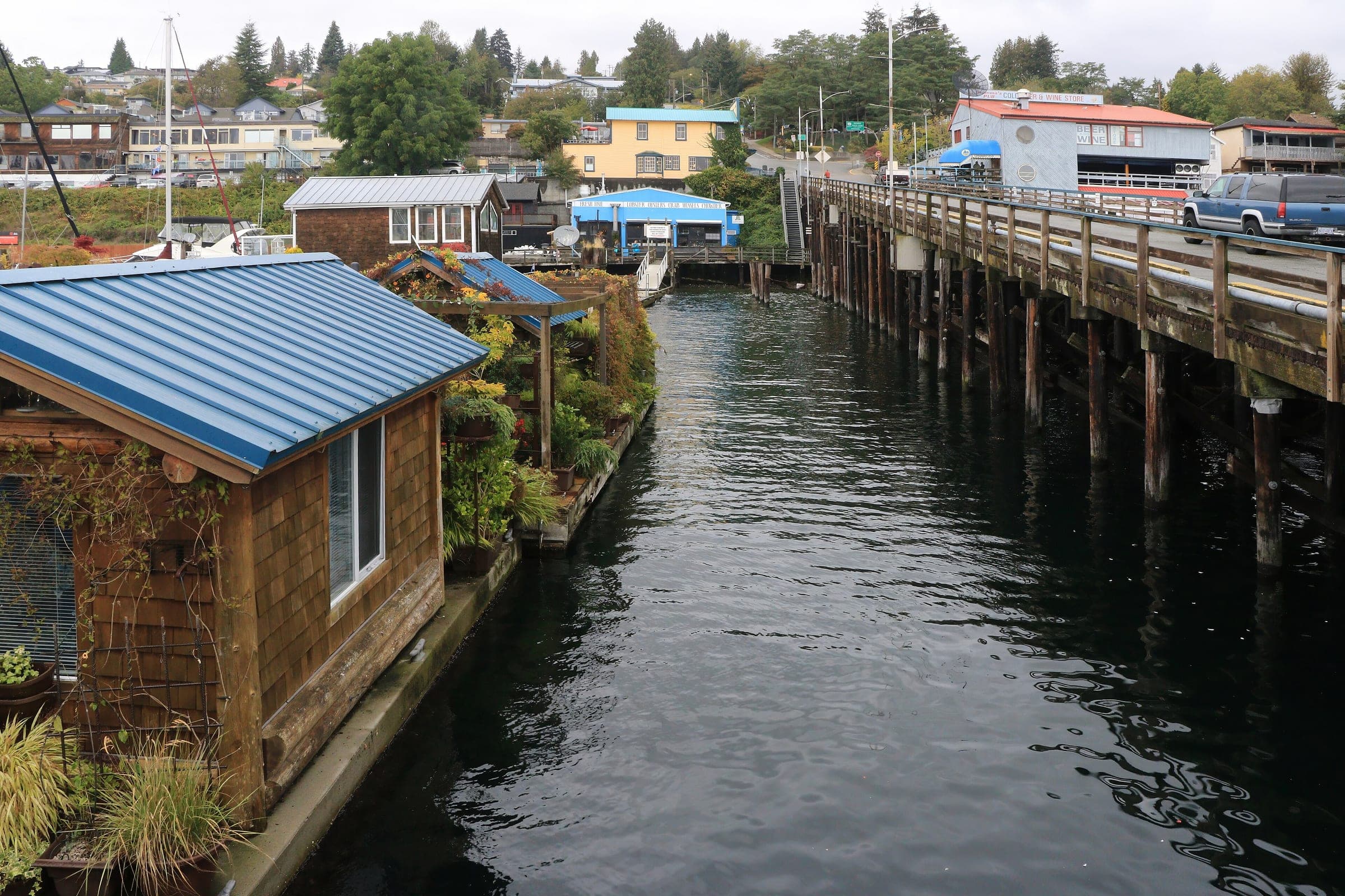 Houseboats line the government pier at Gibsons Landing with the town climbing the hill behind.
