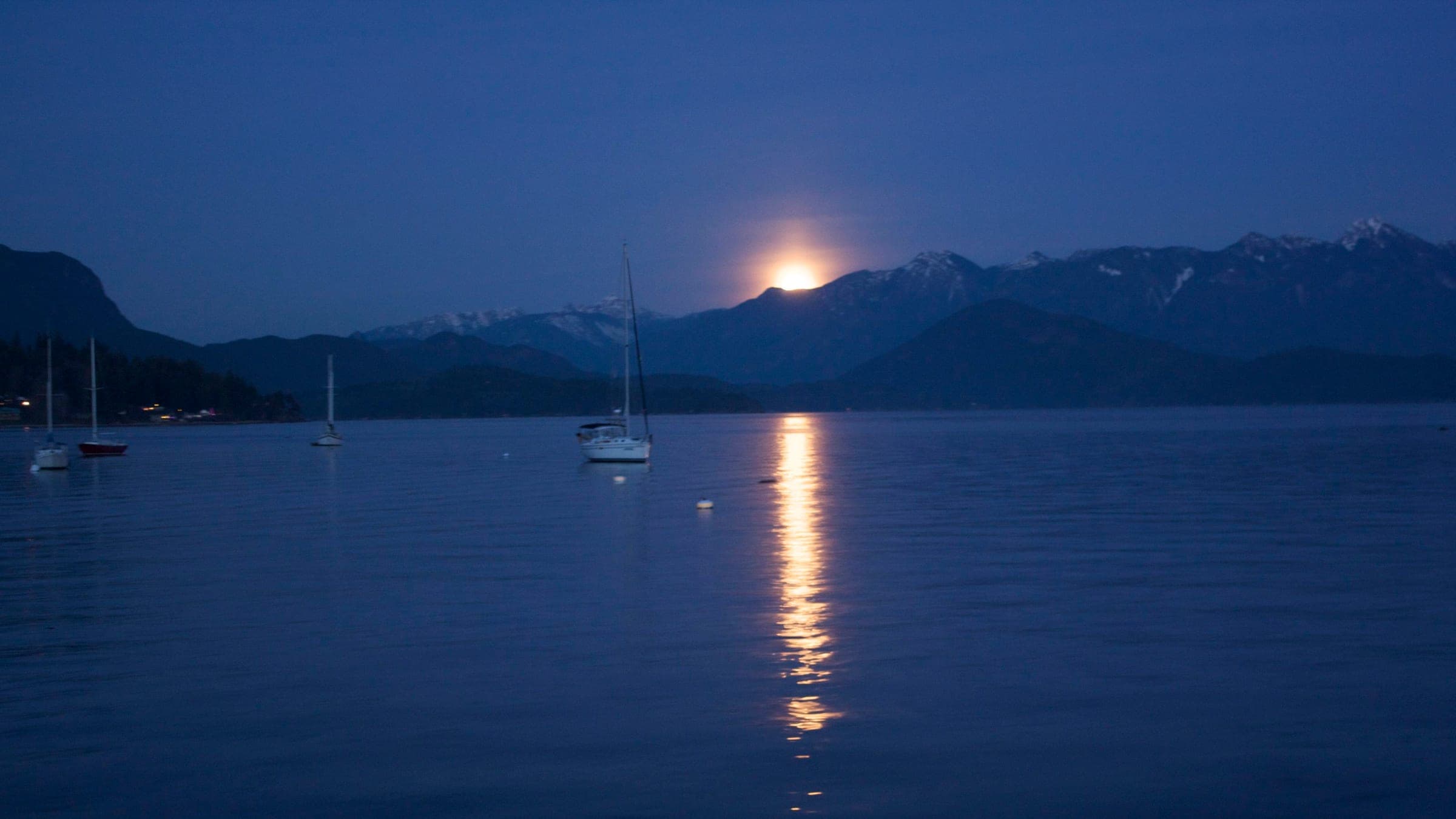 The moon rises over Howe Sound and the snowy Coast Mountains seen from Gibsons in December.