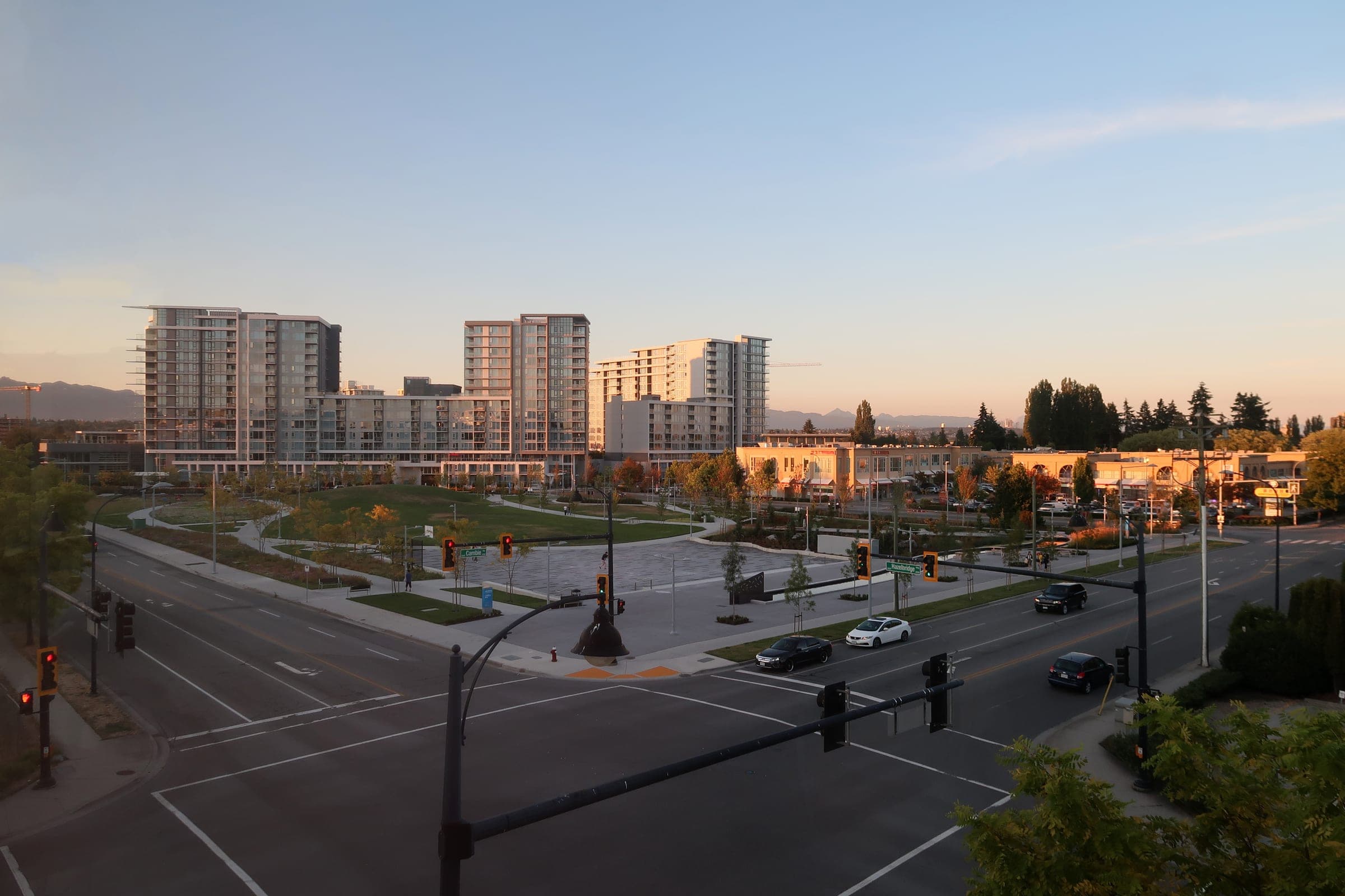 Towers and low malls of Richmond's Golden Village catch the last light at dusk along a wide intersection.