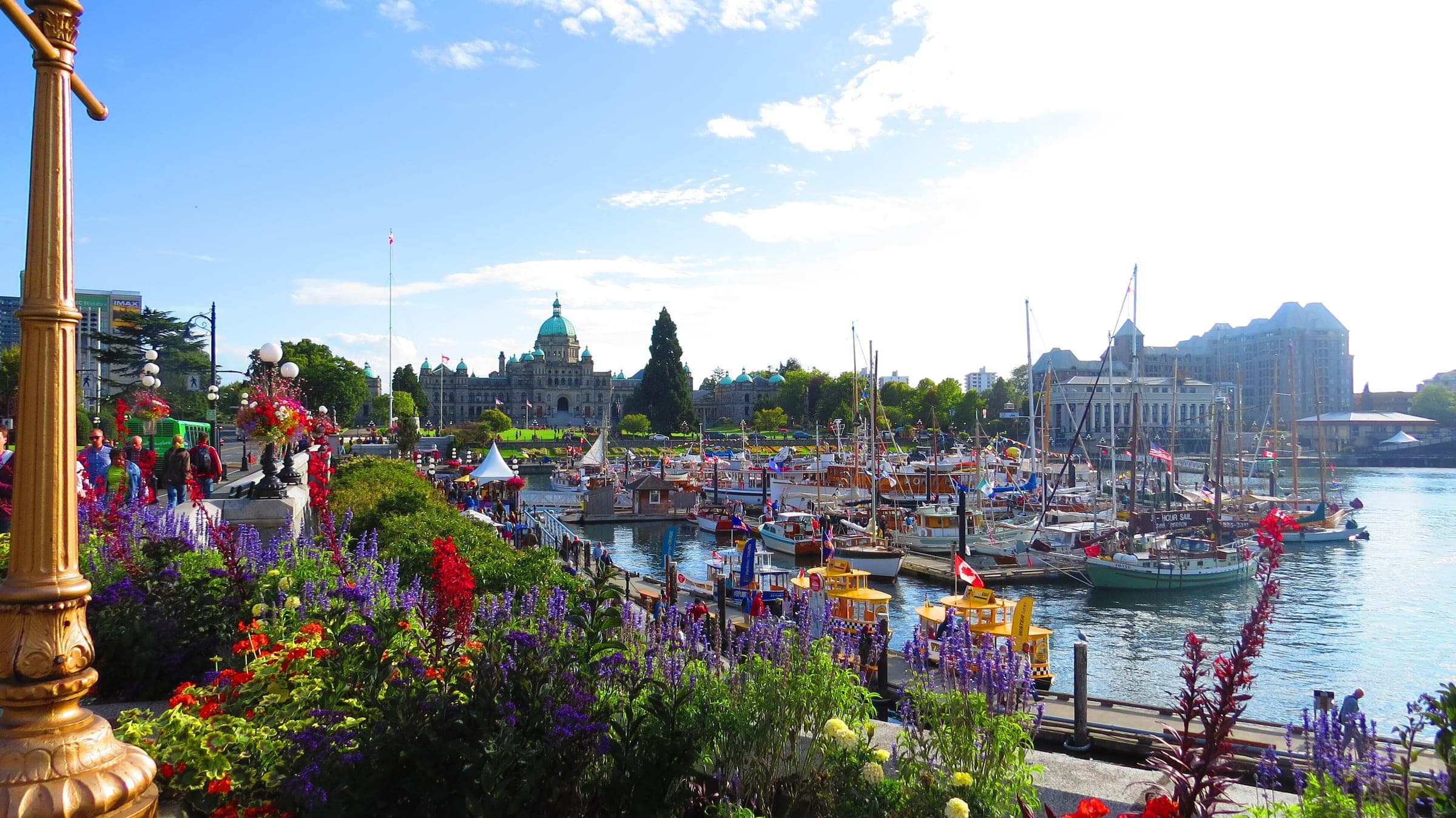 Flower baskets line the Inner Harbour Causeway in Victoria with the BC Parliament Buildings beyond.