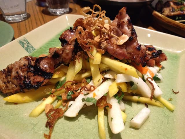 Gỏi xoài at Anh and Chi on Main Street heaps green mango, herbs and fried shallots under grilled chicken.