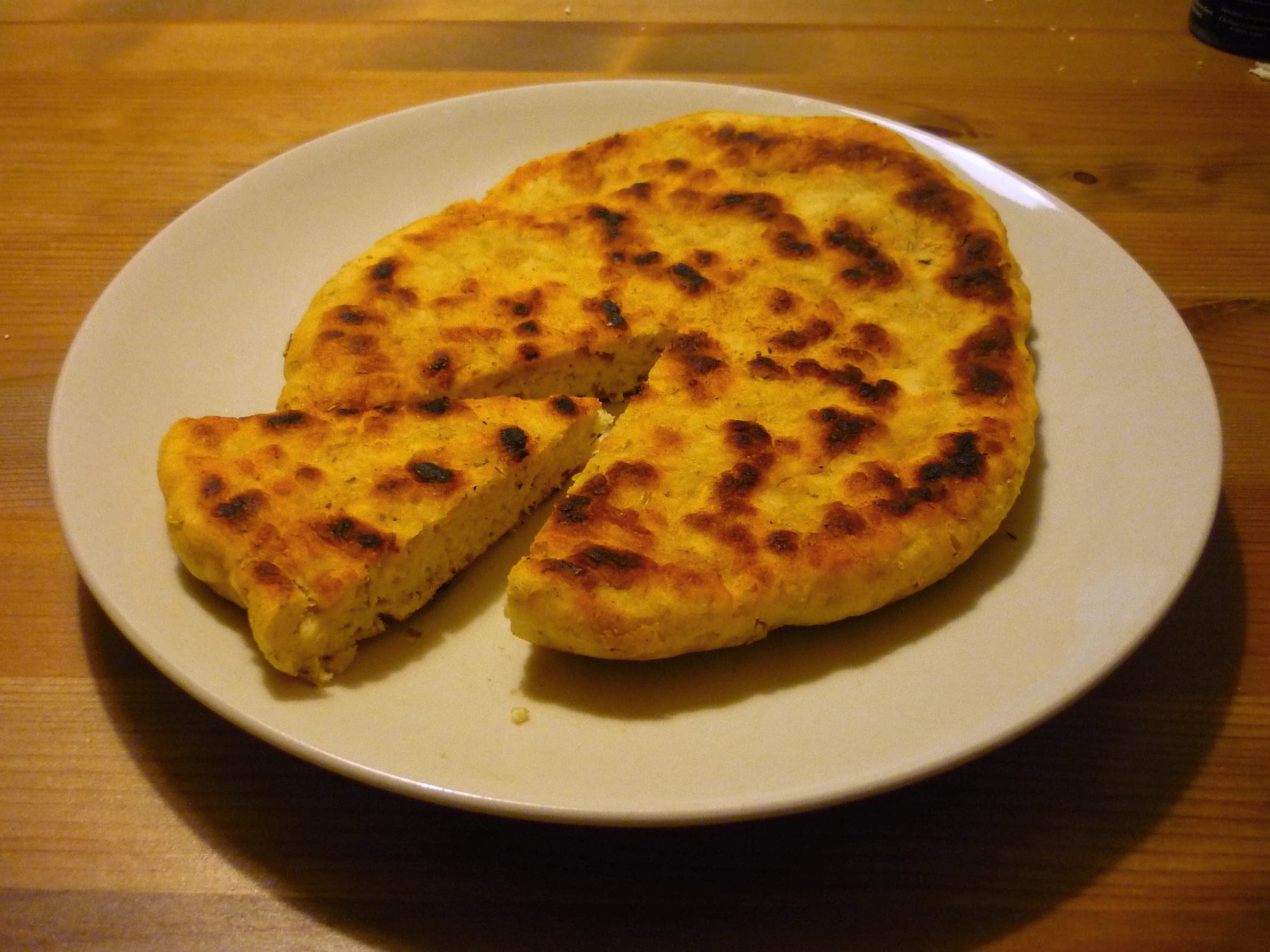A golden bannock cut into wedges on a plate