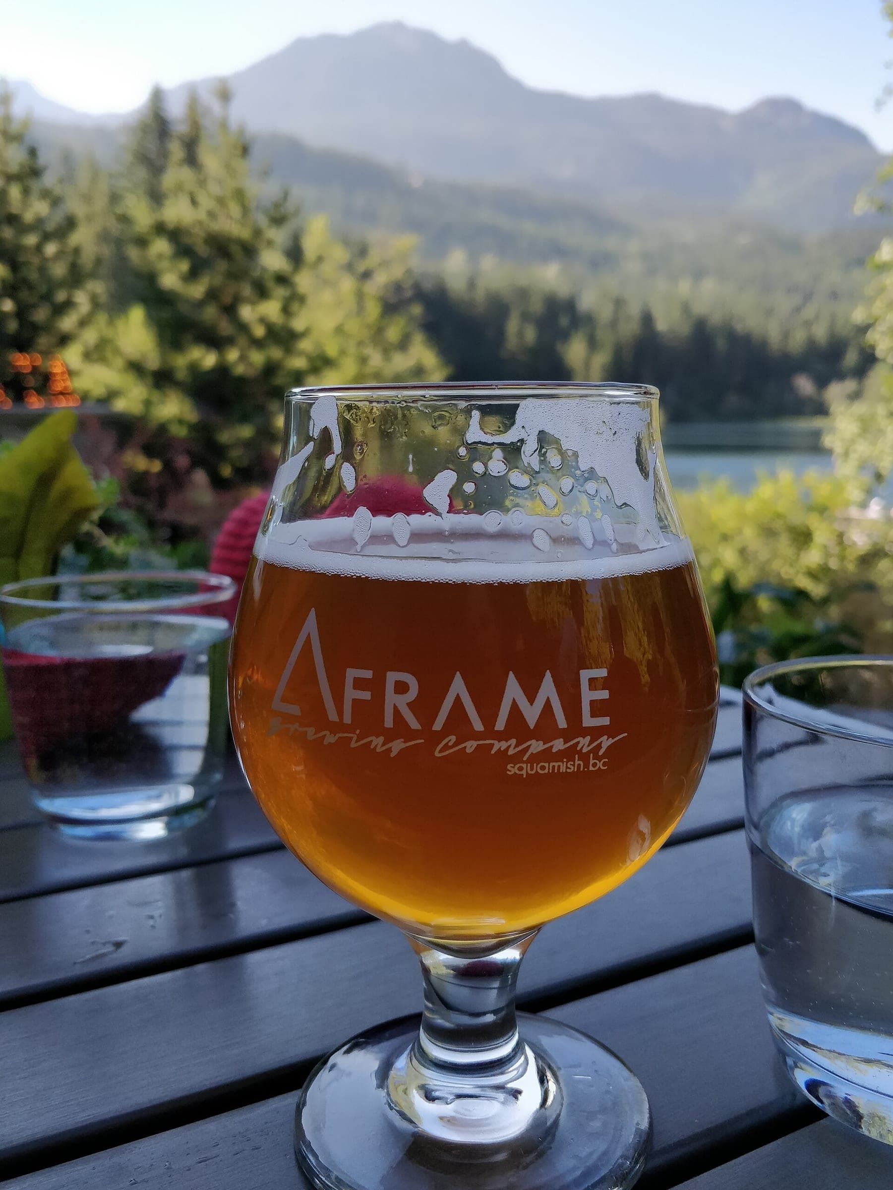 A glass of A-Frame Brewing beer from Squamish sits on the Nita Lake Lodge patio below Whistler's peaks.
