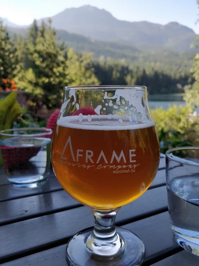 A glass of A-Frame Brewing beer from Squamish sits on the Nita Lake Lodge patio below Whistler's peaks.