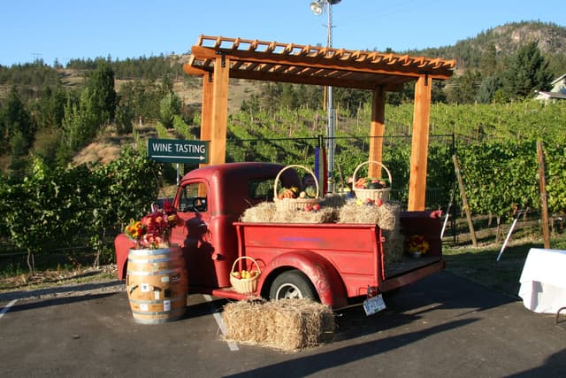 An old red truck loaded with harvest baskets stands by the vines outside La Frenz Winery in Naramata, BC.