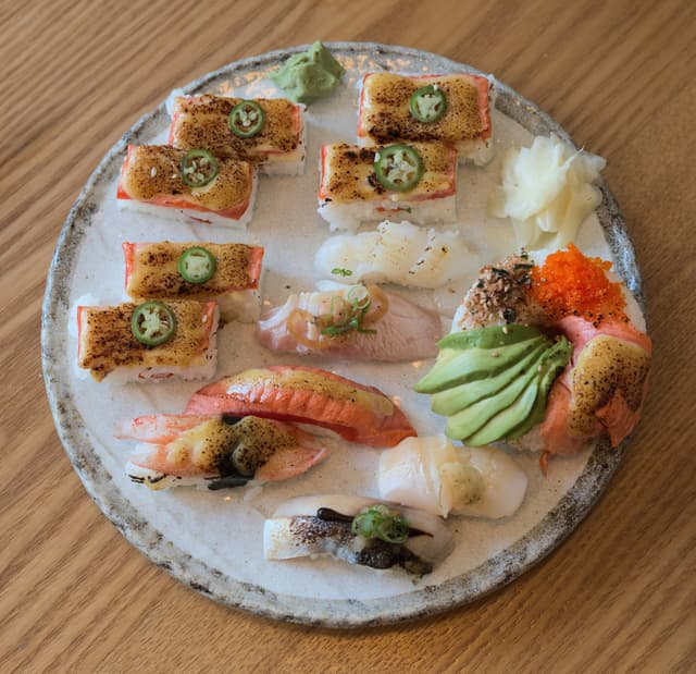 A plate of Vancouver sushi holds torched aburi oshizushi with jalapeño, aburi nigiri and a sushi doughnut.
