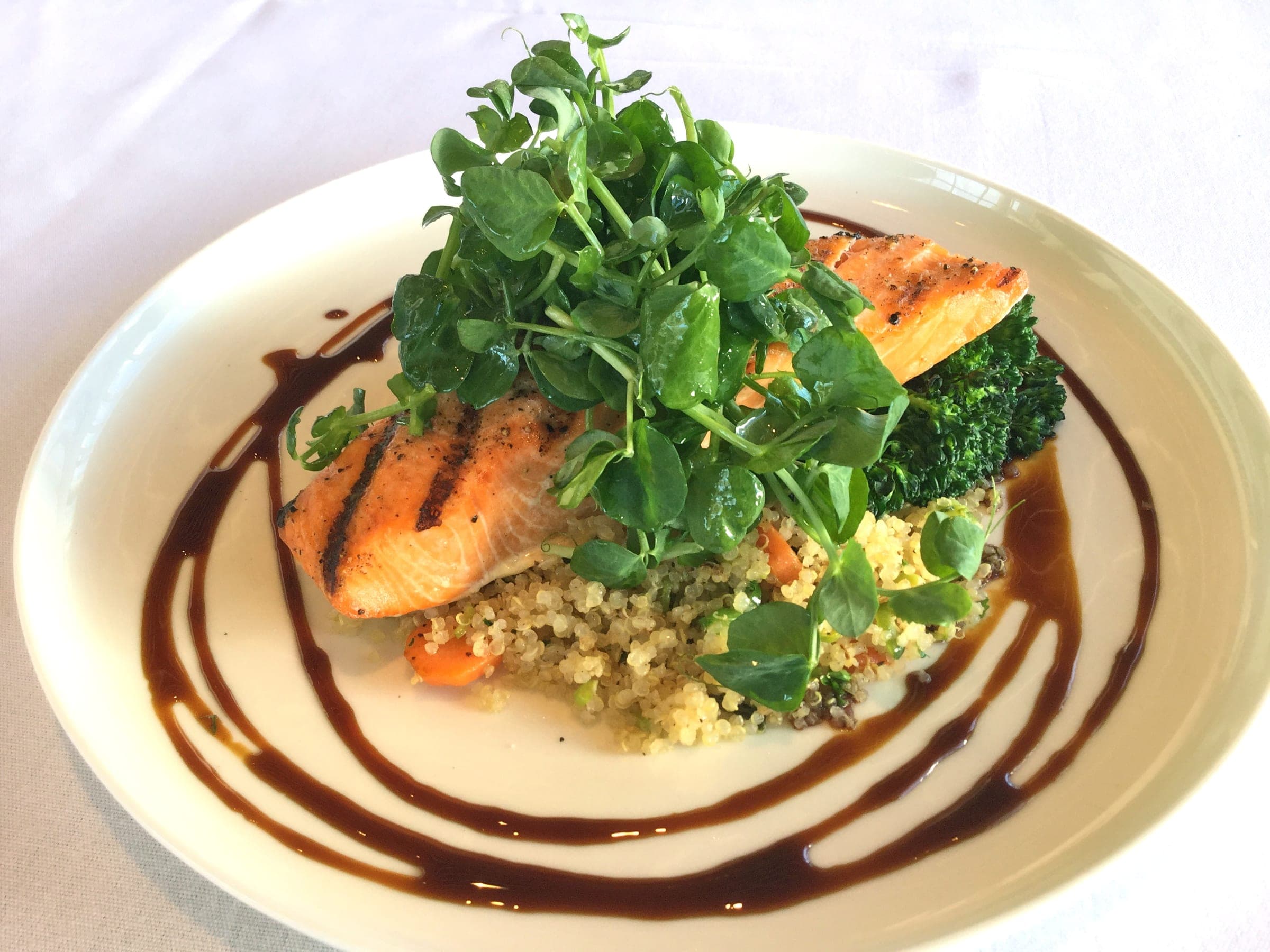 Grilled wild salmon on vegetable quinoa with pea shoots and a maple soy glaze at a Vancouver hotel restaurant.
