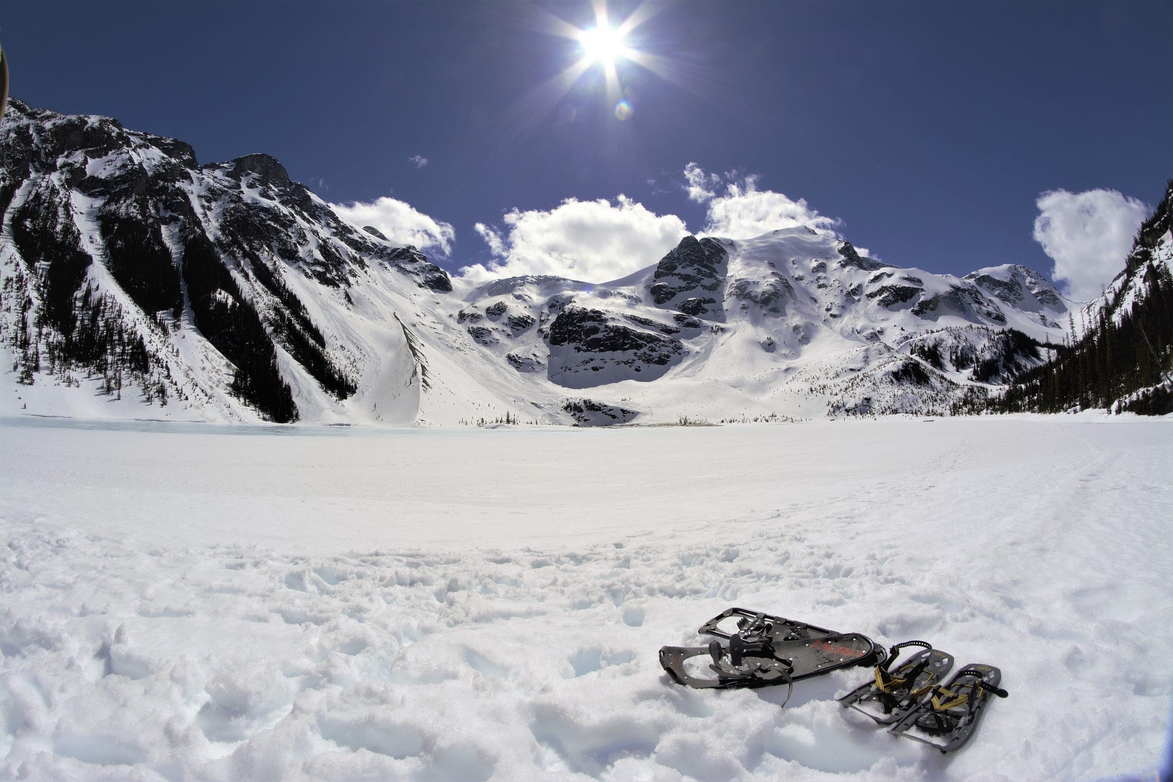Snowshoes rest on a frozen Joffre lake below the snowy cliffs and glaciers of the Joffre Group.