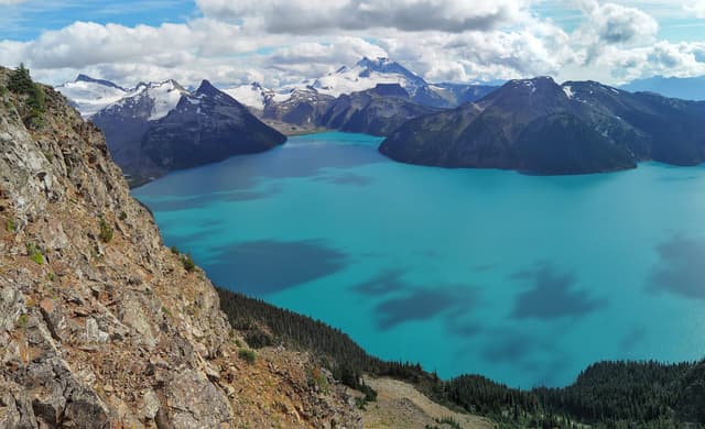 Turquoise Garibaldi Lake spreads below the rocky summit slope of Panorama Ridge in September.