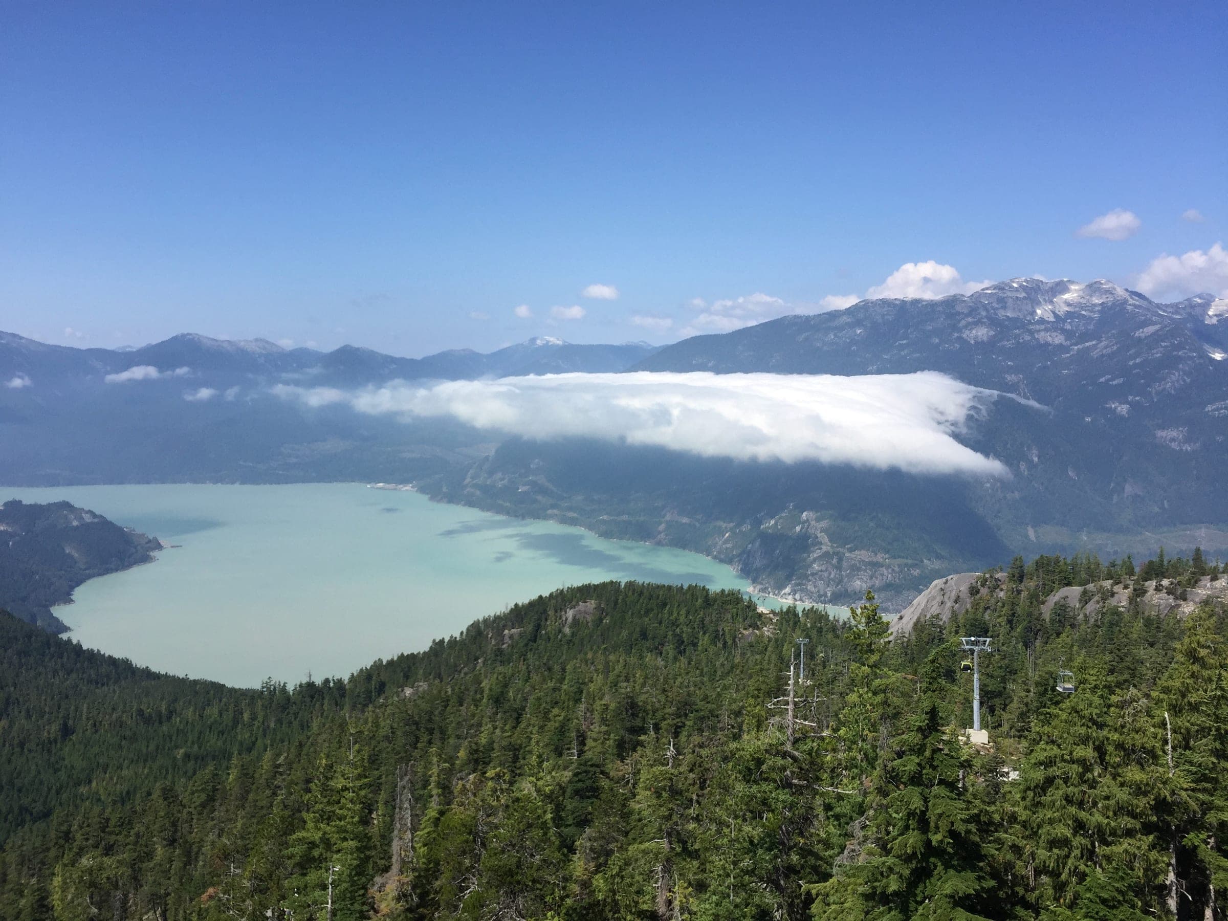 A bank of cloud sits on Howe Sound beyond the gondola towers on the slope the Sea to Summit Trail climbs.