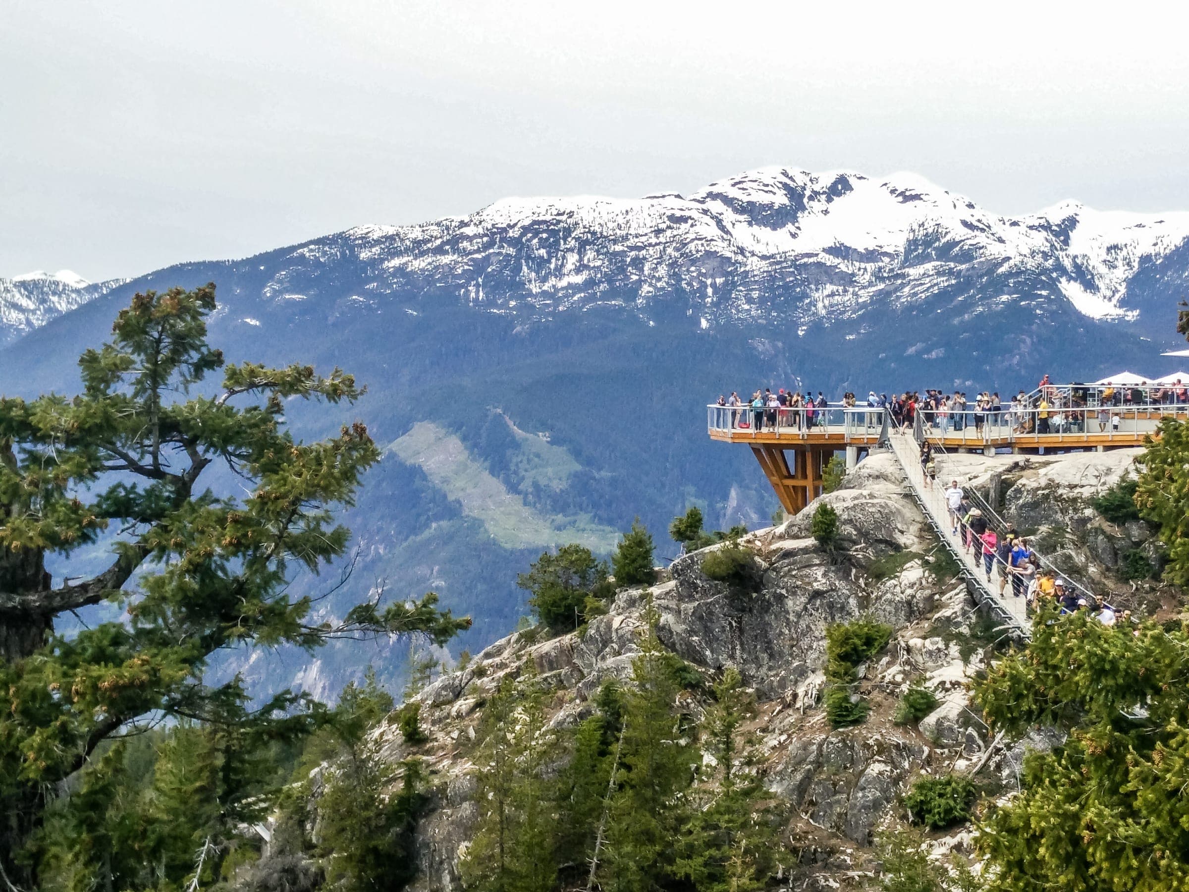 Visitors line the Summit Lodge viewing platform above granite bluffs where the Sea to Summit Trail ends.