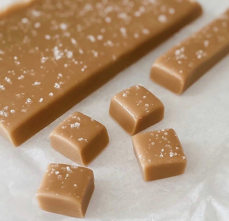 Squares of Charlie Girl Goods salted caramel cut from a slab on parchment paper.