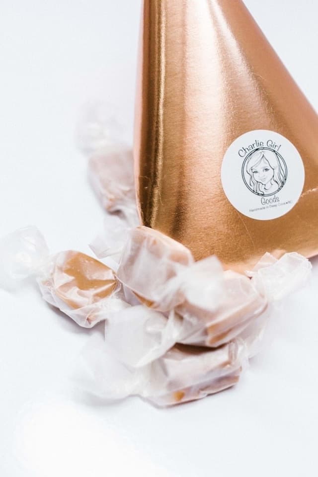 Charlie Girl Goods caramels in wax paper twists spilling from a copper paper cone.