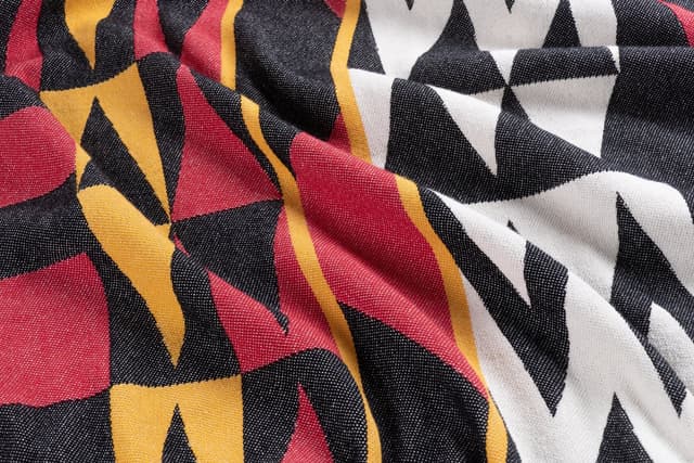 A close view of the Welcome Blanket from Salish Blanket Co., woven in red, gold, black and white.