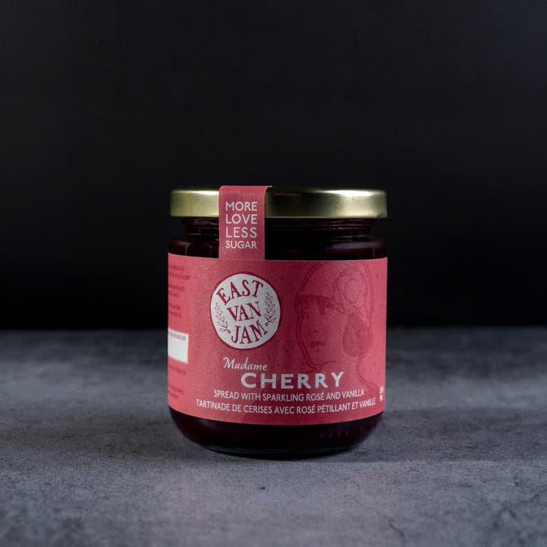 A jar of East Van Jam cherry spread against a dark background.