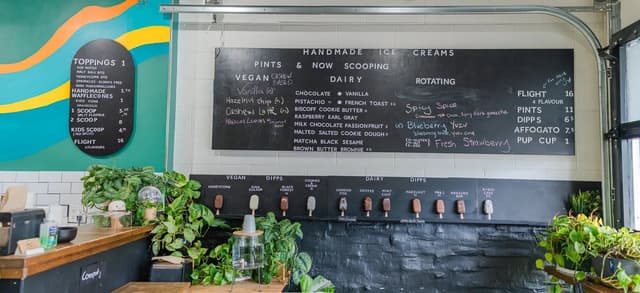 The counter at Melt Confectionary under a chalkboard menu of ice cream flavours and a bright painted wall.
