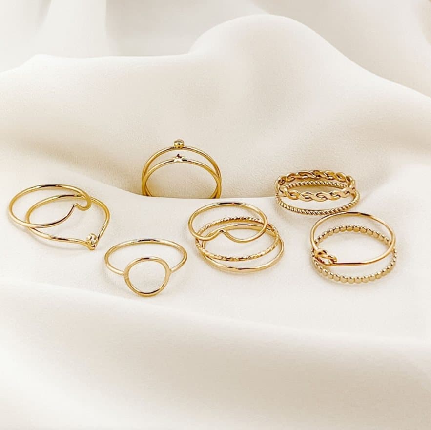 Gold rings from Reminded Designs laid in the folds of cream fabric.