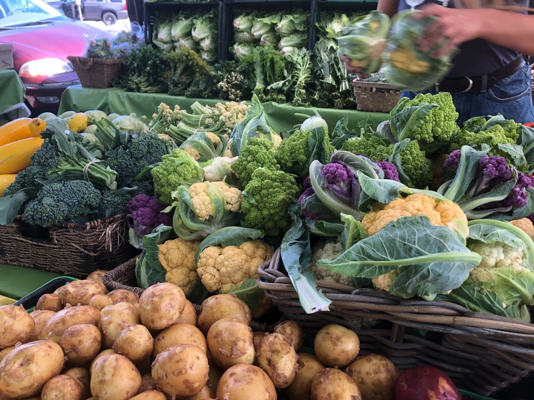 Coloured cauliflower and baskets of potatoes on a stall at the Riley Park Winter Farmers Market.