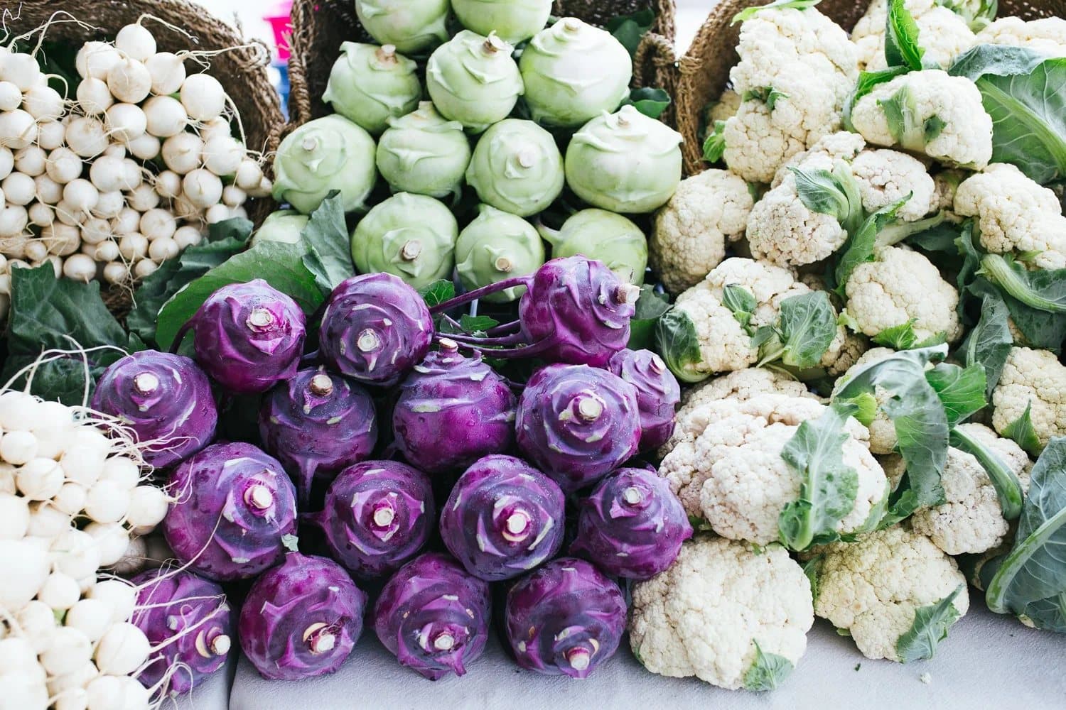 Purple kohlrabi and white cauliflower stacked on a Squamish Farmers Market stall.
