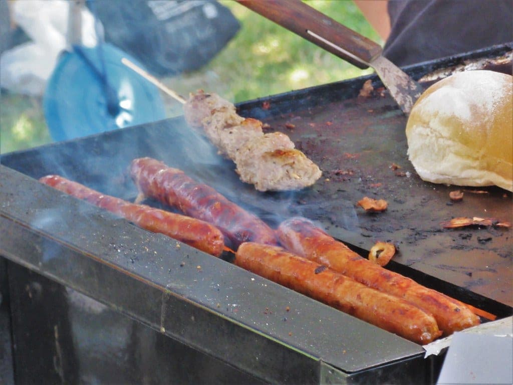 Sausages and a bun on a hot griddle at a food stall in the Trout Lake Farmers Market