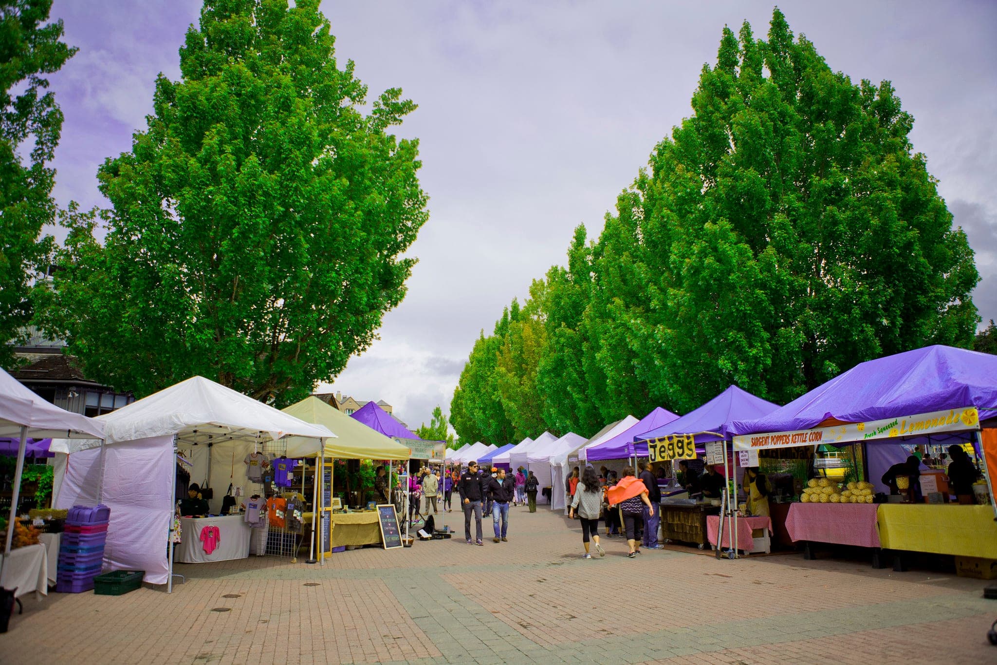 Market tents line the Upper Village Stroll at the Whistler Farmers Market on a July Sunday.