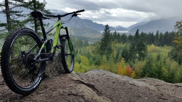 A full-suspension mountain bike rests on a rock above Squamish with the valley and mountains behind.