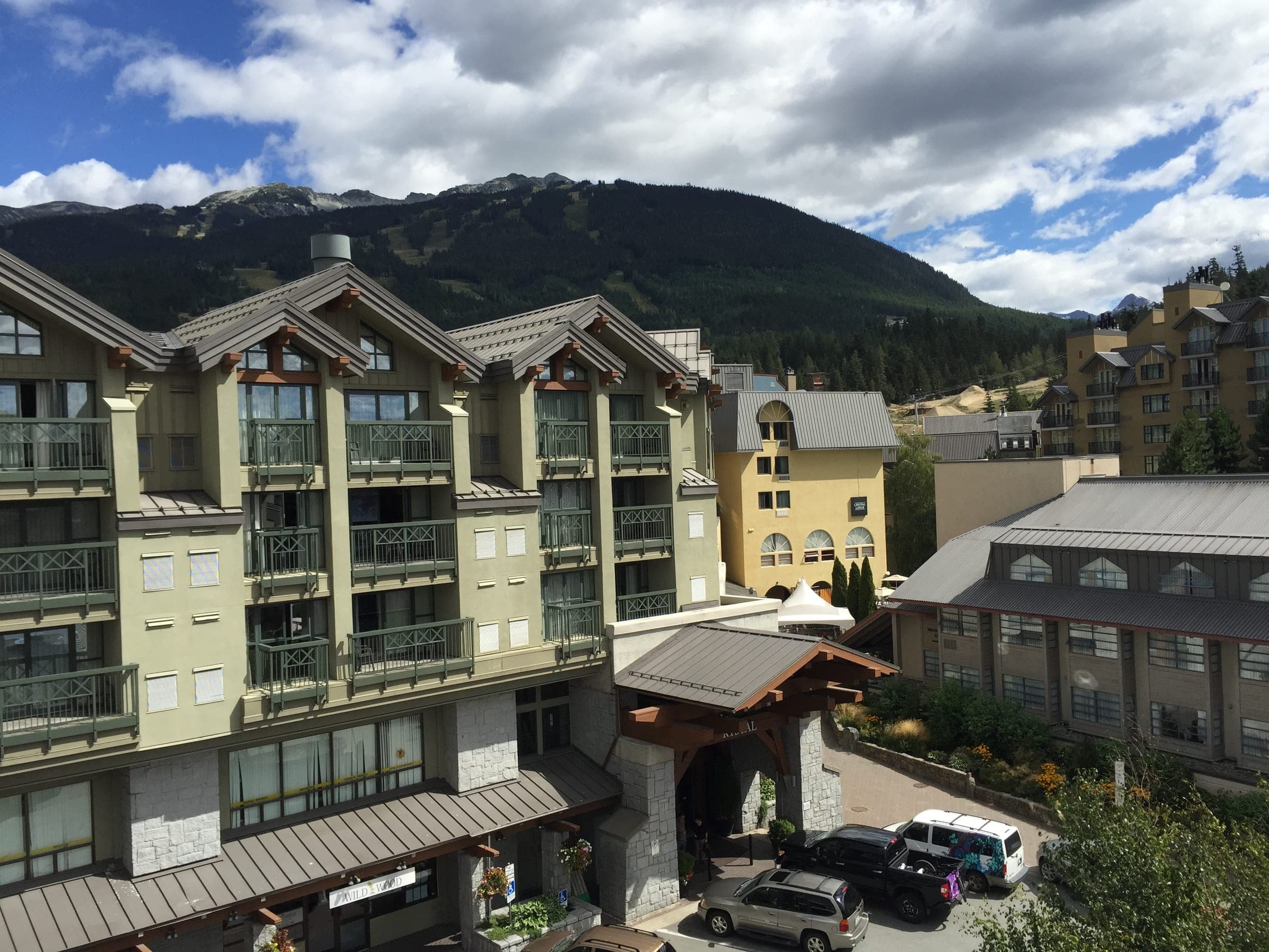 Whistler Village buildings stand below forested mountains near the Village Green.