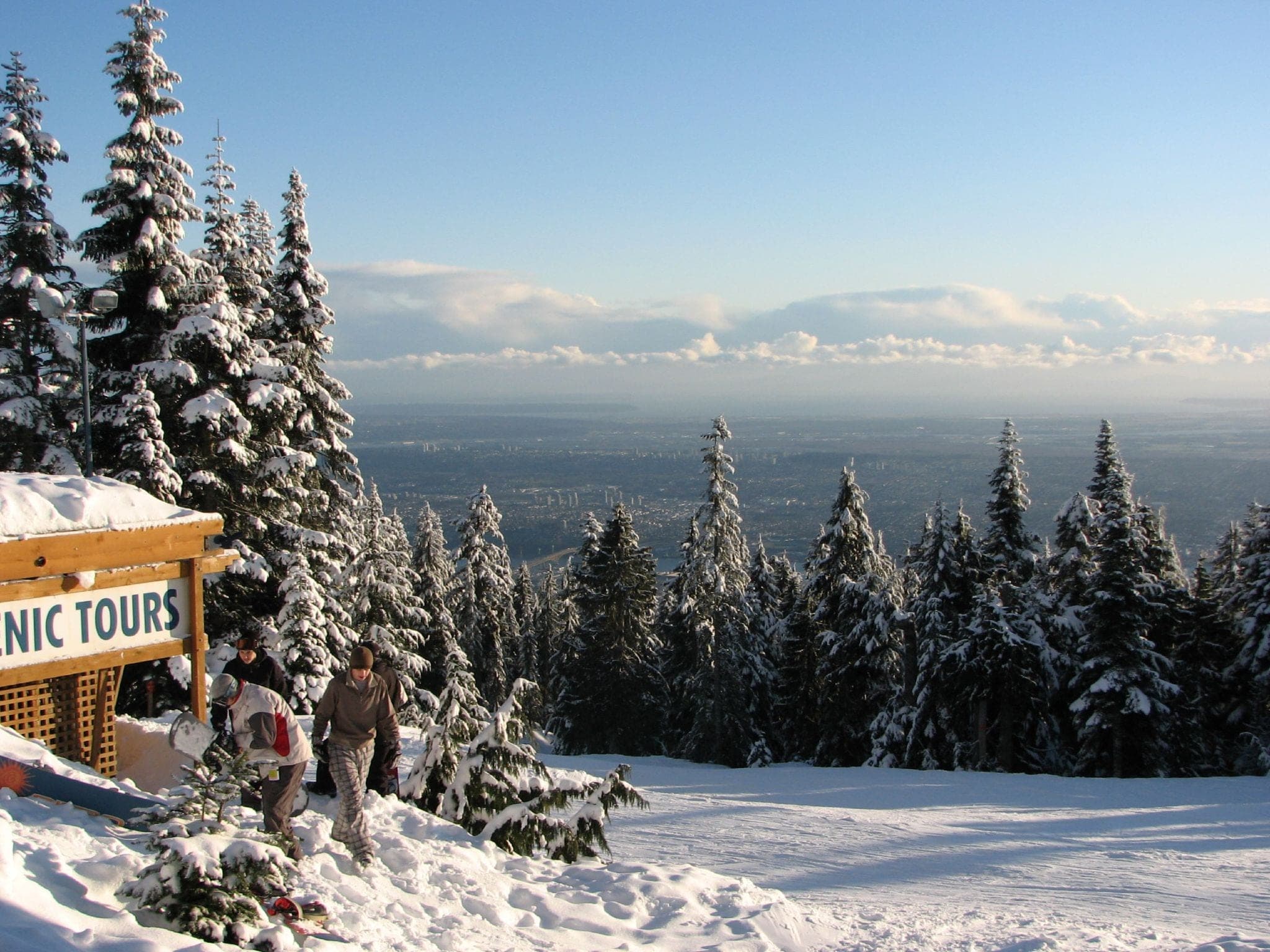 Snow-loaded firs frame the view from the Grouse Mountain summit across Metro Vancouver on a January afternoon.