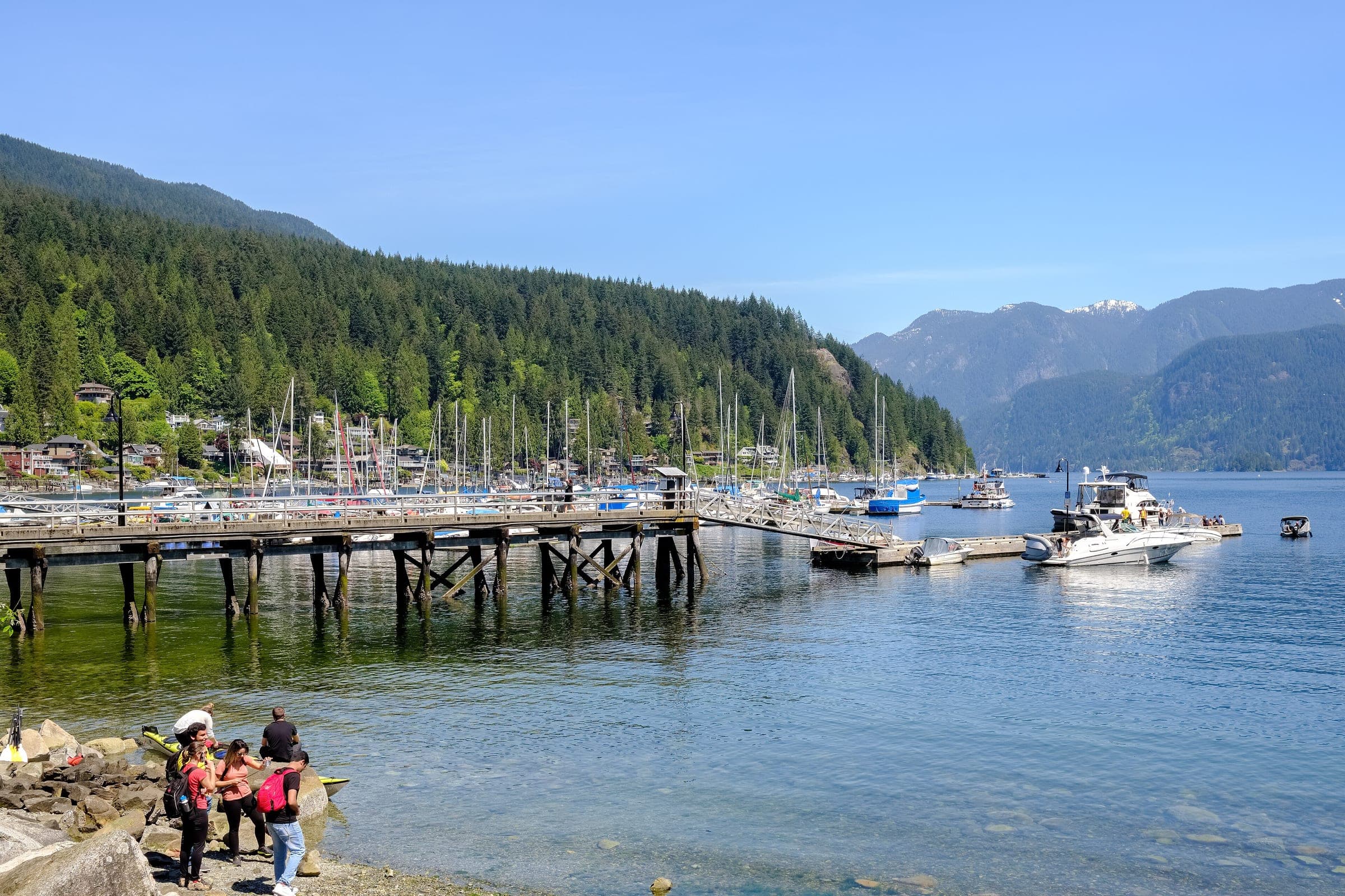 The Deep Cove pier and marina sit below forested slopes where the cove opens onto Indian Arm.
