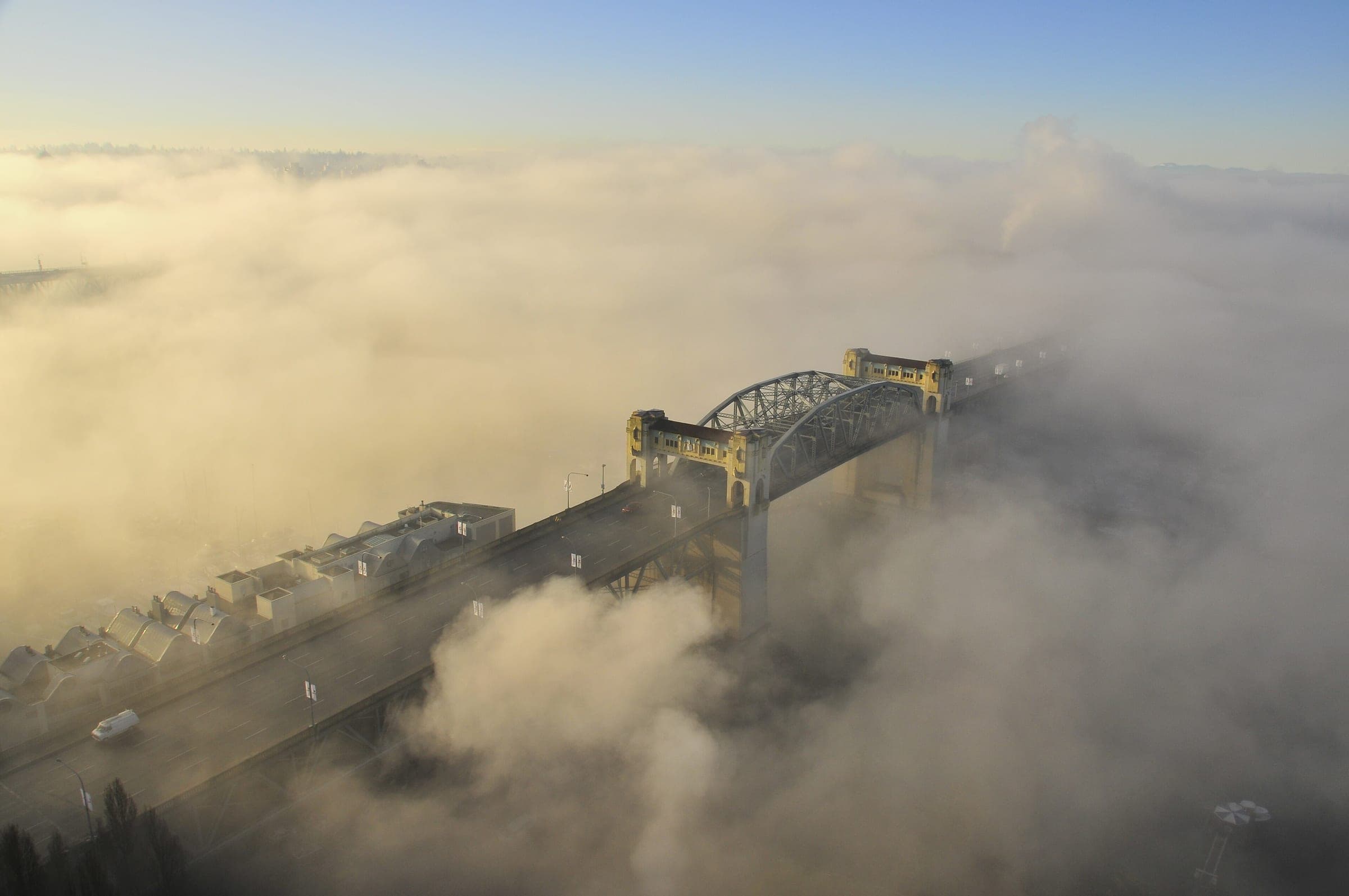 January fog pours over False Creek and wraps the steel arches of the Burrard Street Bridge.
