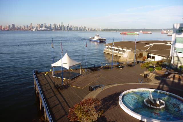 The Lonsdale Quay pier and fountain look across Burrard Inlet to the downtown Vancouver skyline.