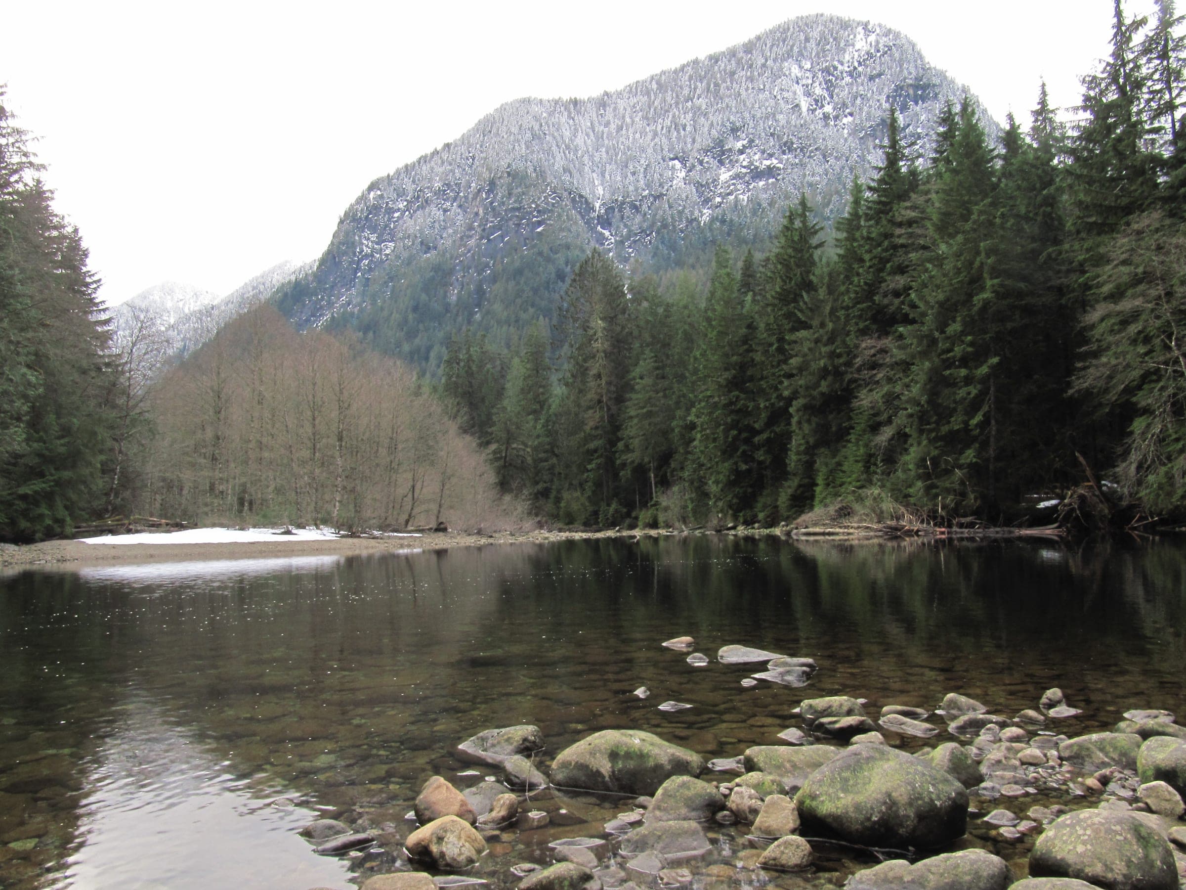 Fresh snow dusts the peak above a calm pool on the Seymour River in the Lower Seymour Conservation Reserve.