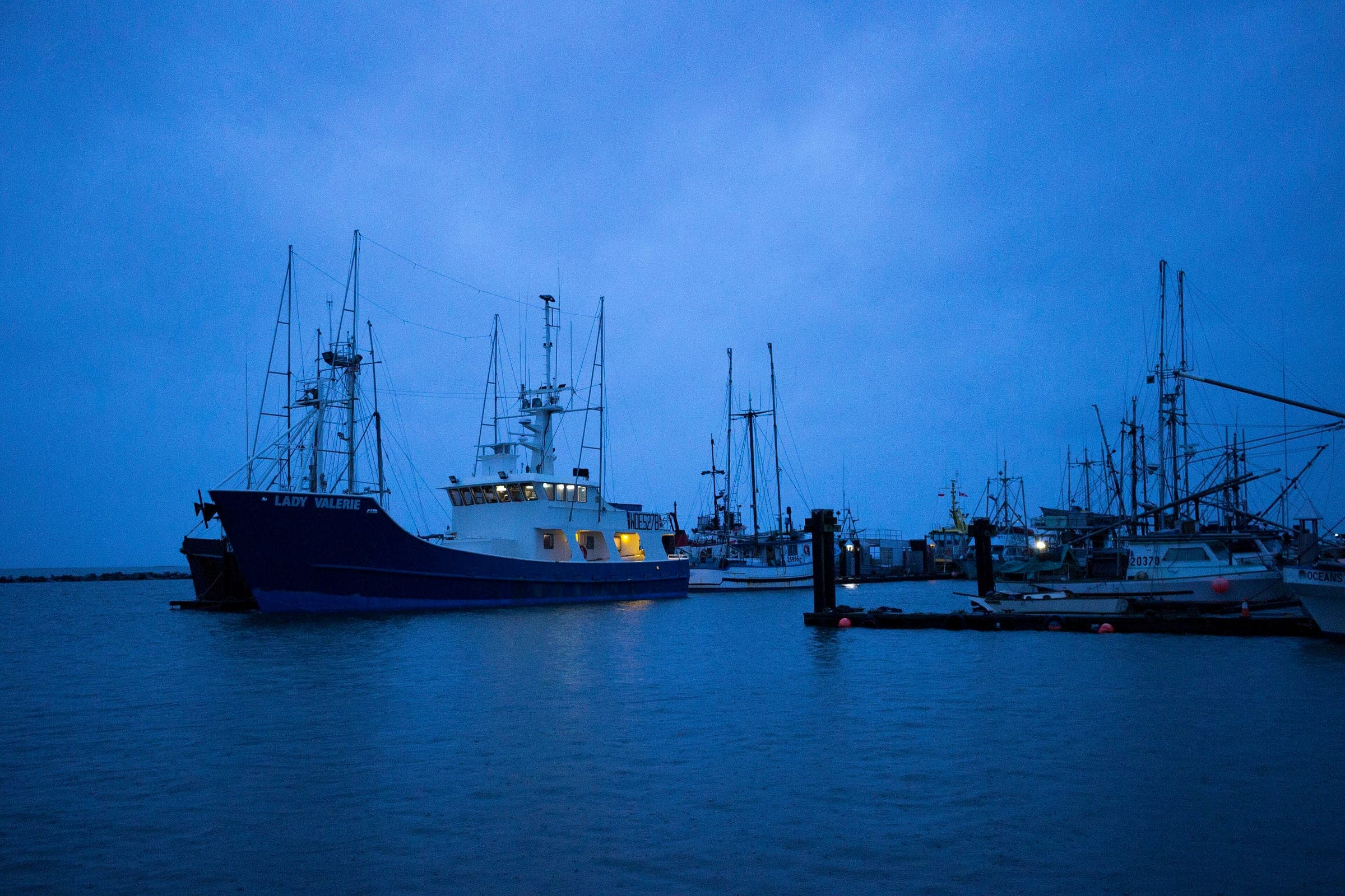 A fishing boat with its deck lights on rests at the Steveston fishing wharf under a stormy November dusk.