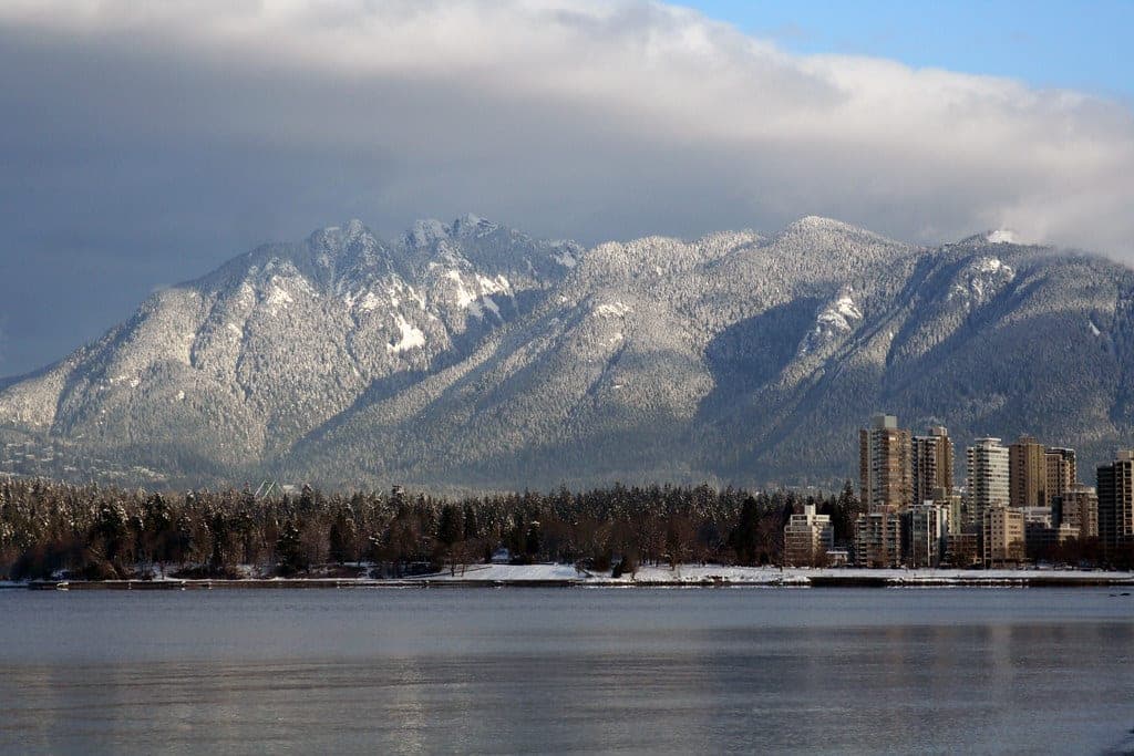 Fresh snow covers the North Shore mountains above Stanley Park and the West End across English Bay from Kitsilano.