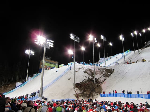 Floodlights shine on the Cypress Mountain aerials hill as a crowd watches the 2010 Olympic freestyle event.