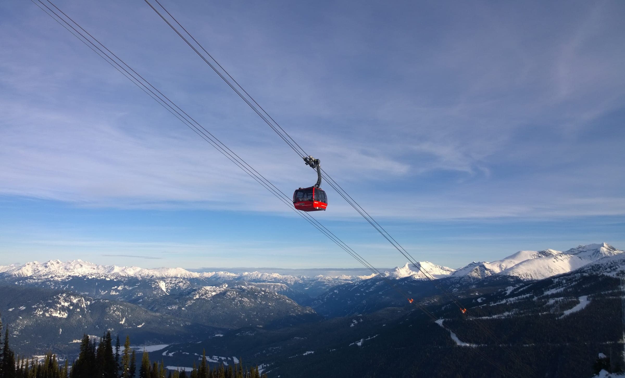 A red Peak 2 Peak Gondola cabin crosses the valley between Whistler and Blackcomb on a winter morning.