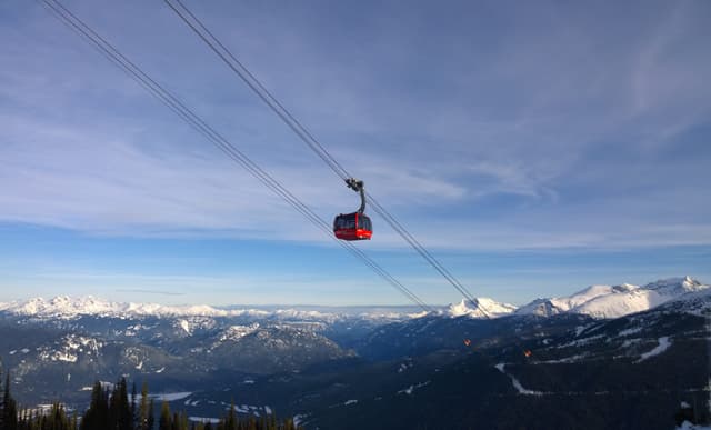 A red Peak 2 Peak Gondola cabin crosses the valley between Whistler and Blackcomb on a winter morning.