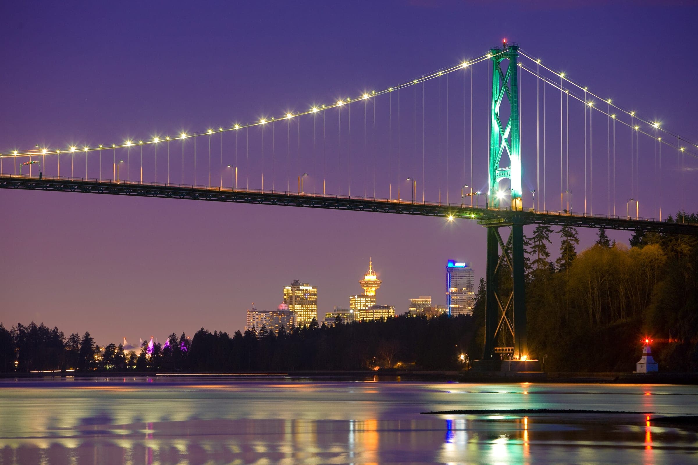 The Lions Gate Bridge lights up at dusk across Burrard Inlet from the Ambleside shore in West Vancouver.