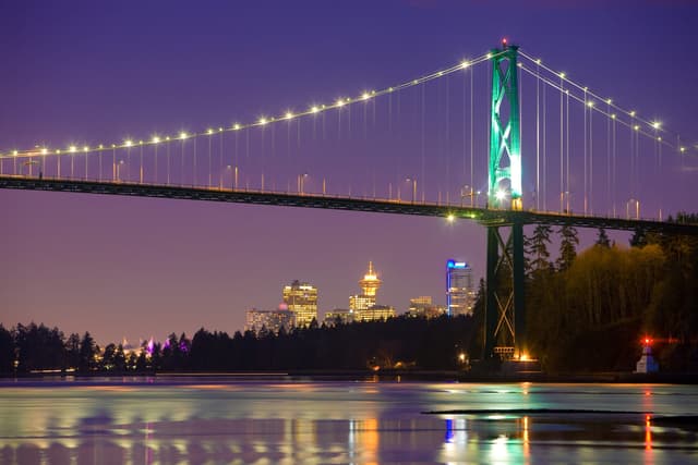 The Lions Gate Bridge lights up at dusk across Burrard Inlet from the Ambleside shore in West Vancouver.