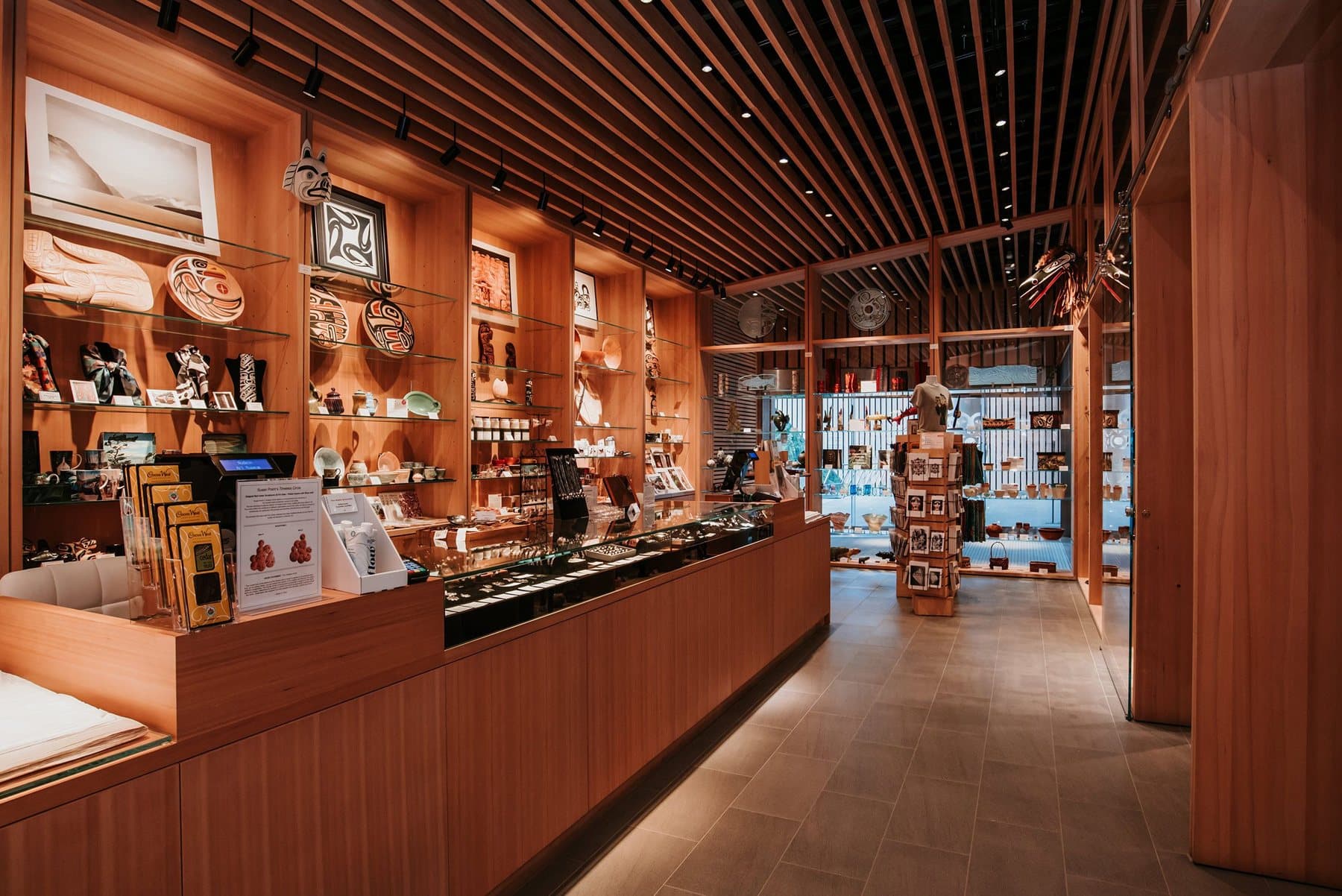 Interior of the Audain Art Museum Shop with wood shelving, display cases and a long counter.