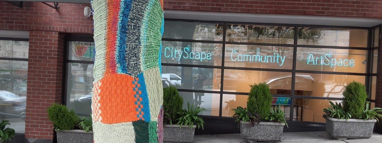 CityScape Community ArtSpace storefront with a yarn-wrapped tree trunk on the sidewalk.