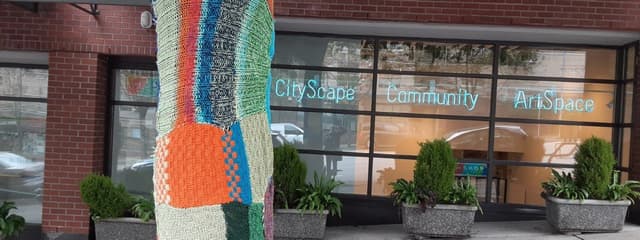 CityScape Community ArtSpace storefront with a yarn-wrapped tree trunk on the sidewalk.