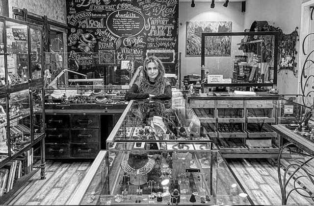 Inside the Juvelisto jewellery shop with glass display counters and a chalkboard wall behind.
