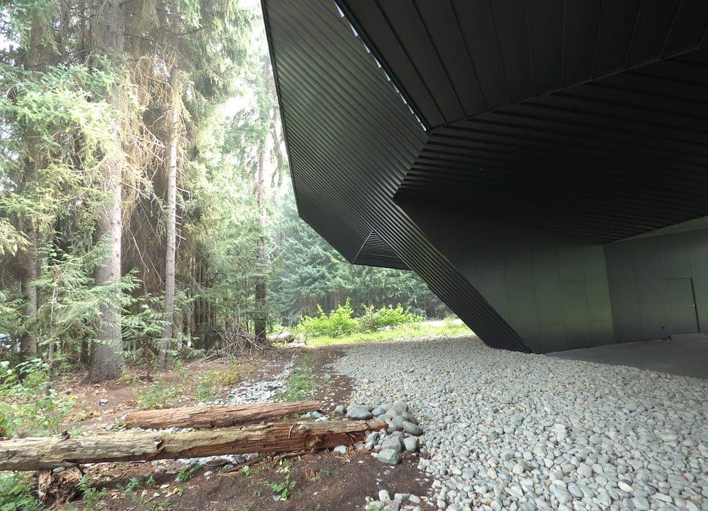 The black-clad wing of the Audain Art Museum in Whistler juts out over a bed of river stones in the forest.