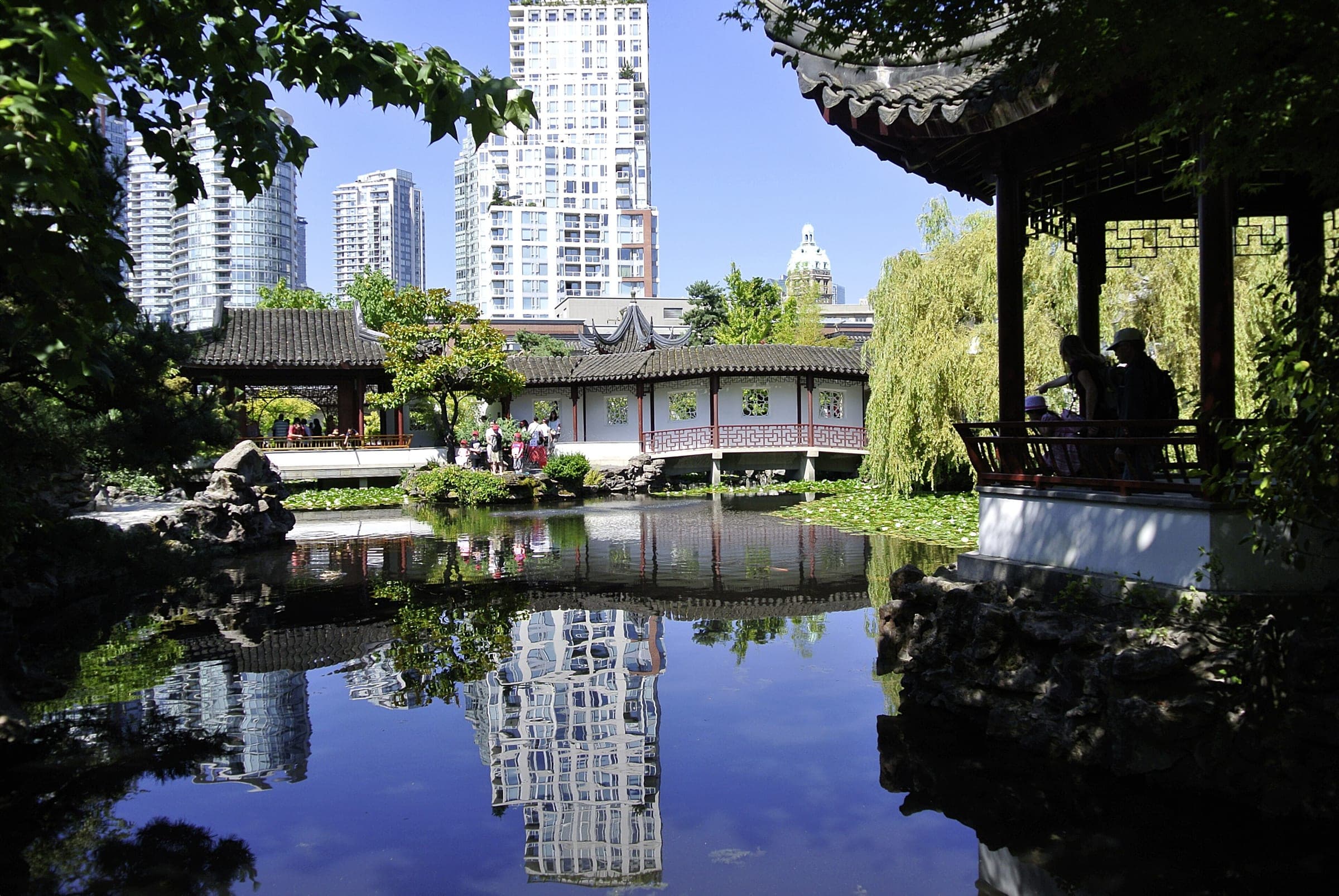 Downtown towers show in the still pond between the covered walkways of the Dr. Sun Yat-Sen Classical Chinese Garden.