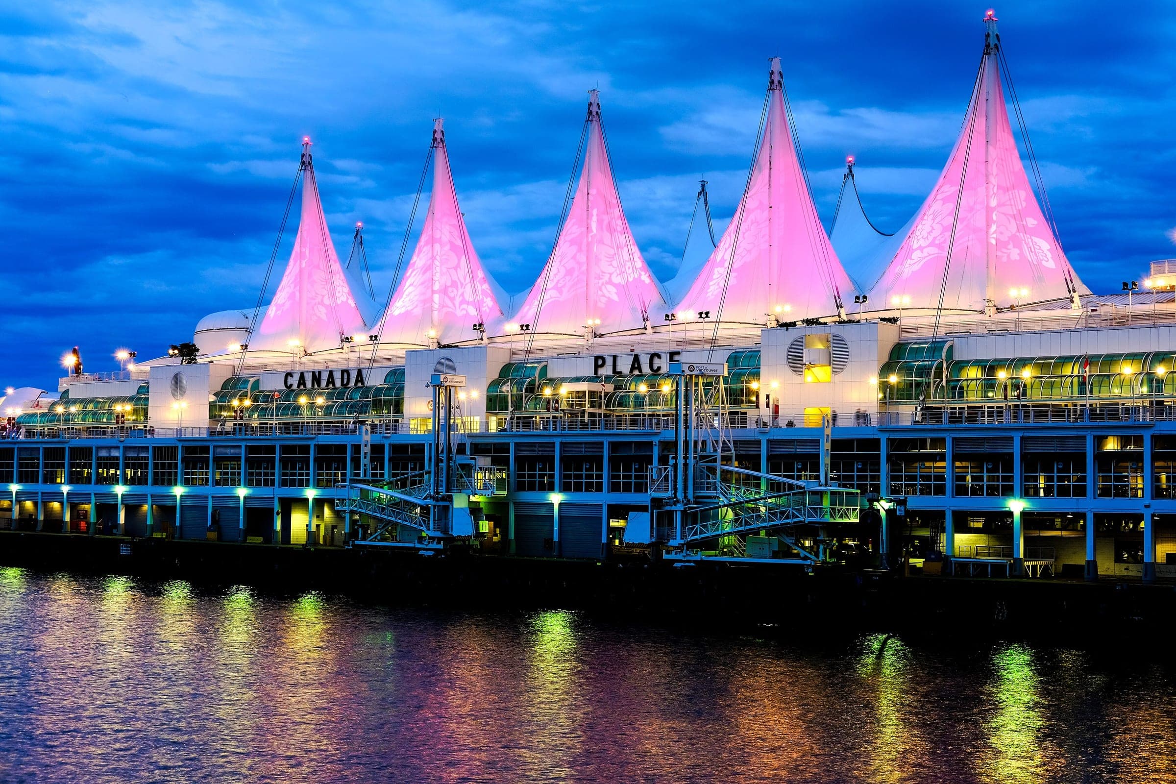 The white sails of Canada Place glow pink and blue at dusk over Vancouver Harbour.