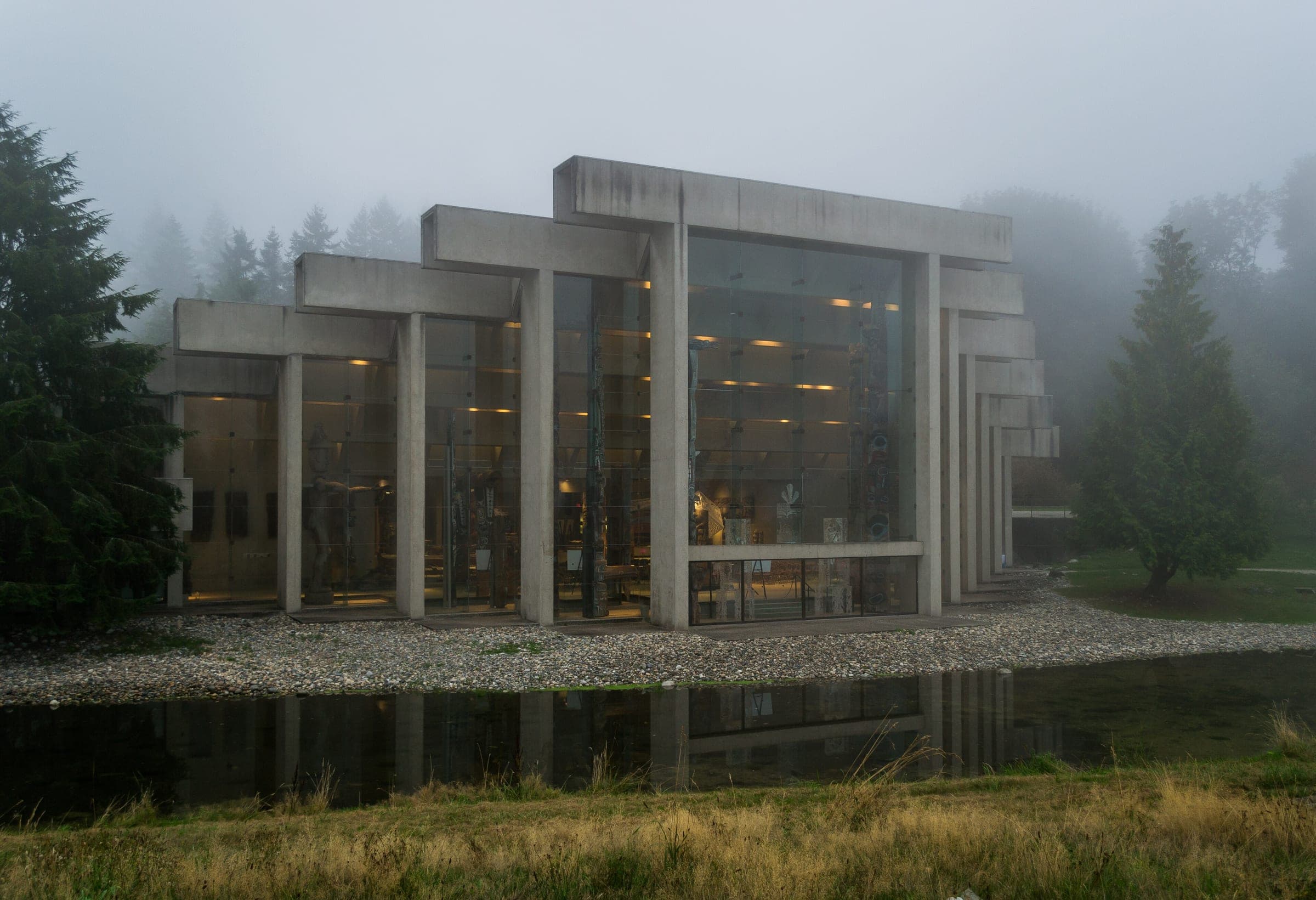 Fog hangs over the Museum of Anthropology at UBC as its concrete frame doubles in the pond.